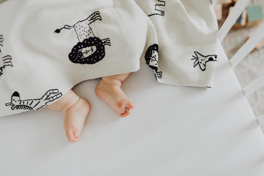 Baby under dyne med fødderne ude